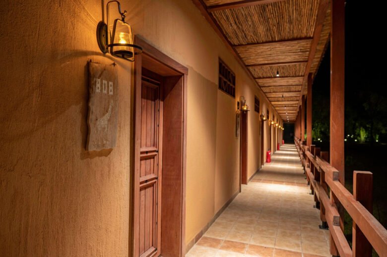 Elegant night-lit corridor and balcony walkway lined with room entrances at Entikko Safari Lodge near Murchison Falls Uganda