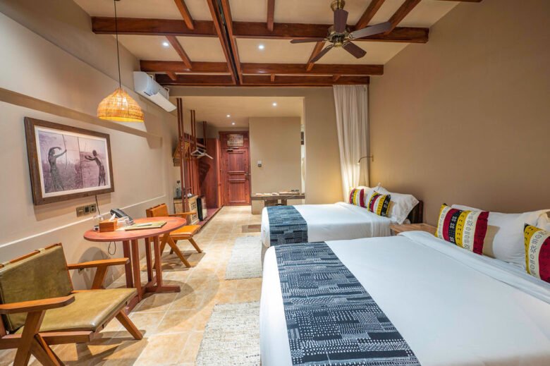 Spacious luxury twin bedroom with wooden beam ceiling and warm lighting at Entikko Safari Lodge near Murchison Falls Uganda