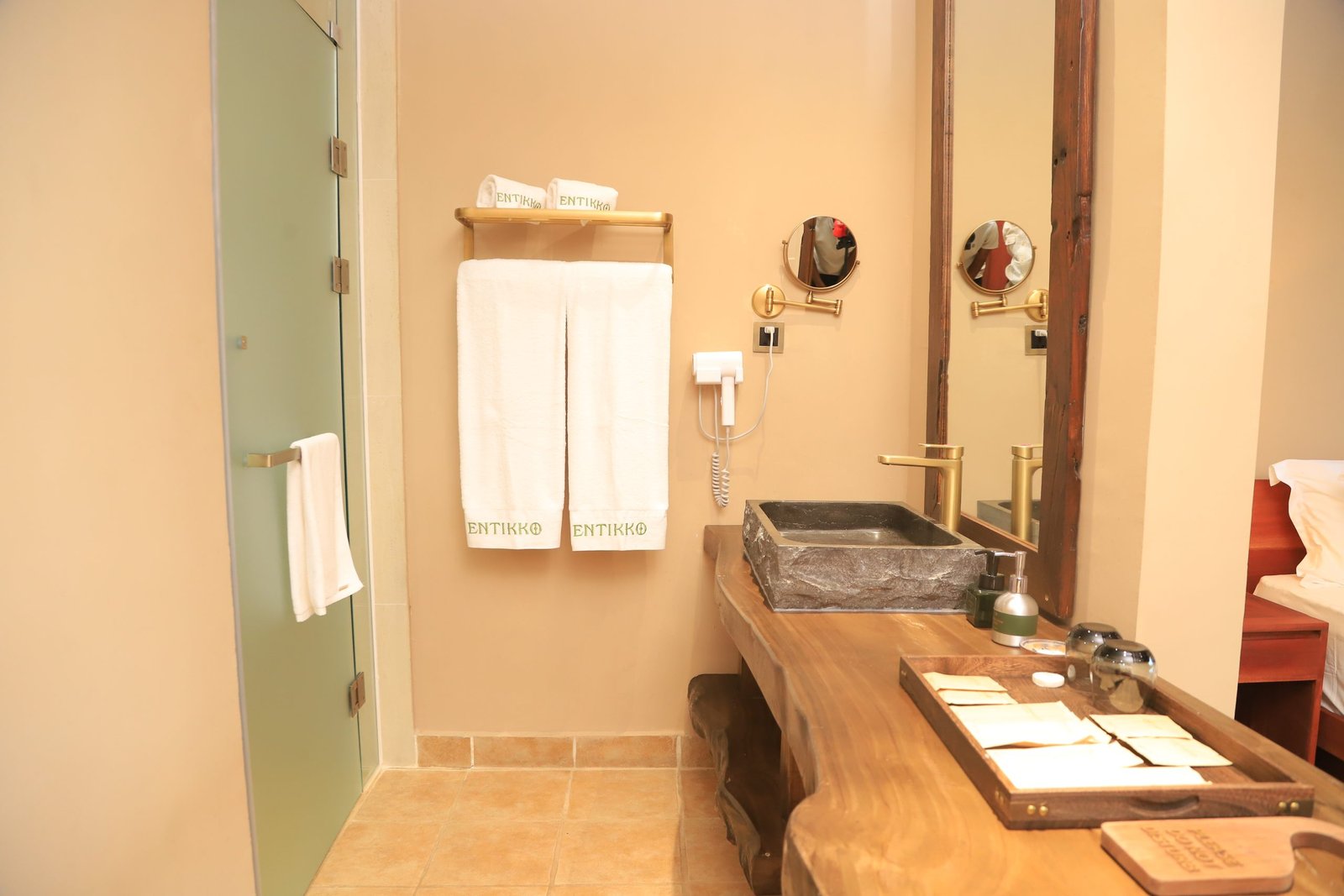 Private ensuite bathroom with tiled walls and rainfall shower at Entikko Safari Lodge single room