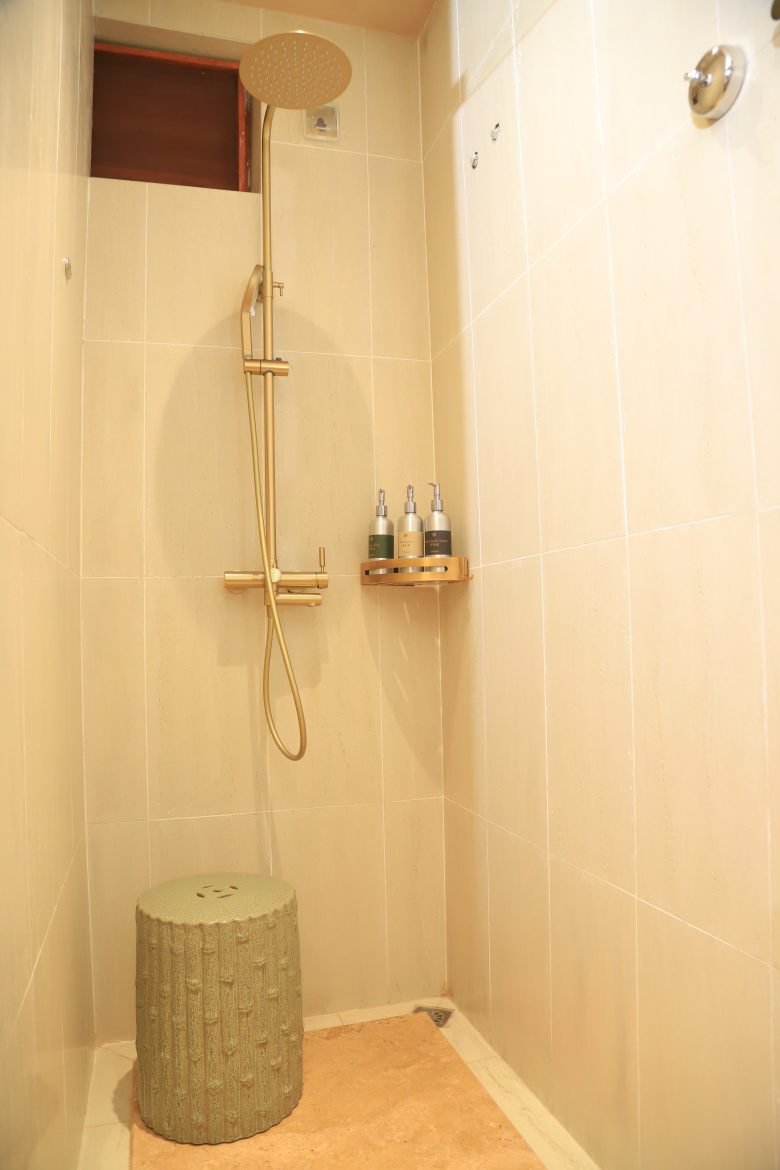 Private ensuite bathroom with shampoo bottles and soap on amenity deck with tiled walls and rainfall shower at Entikko Safari Lodge single room
