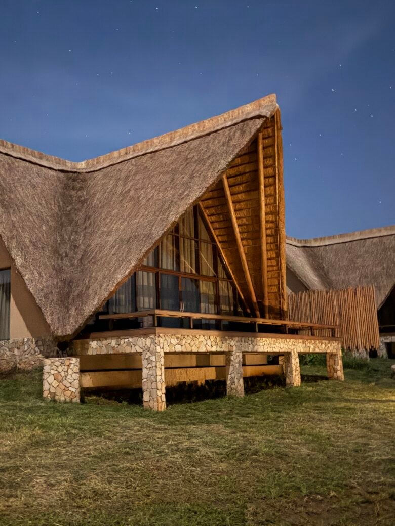 Exterior view of the Family Cottage at Entikko Safari Lodge with thatched A-frame roof at dusk