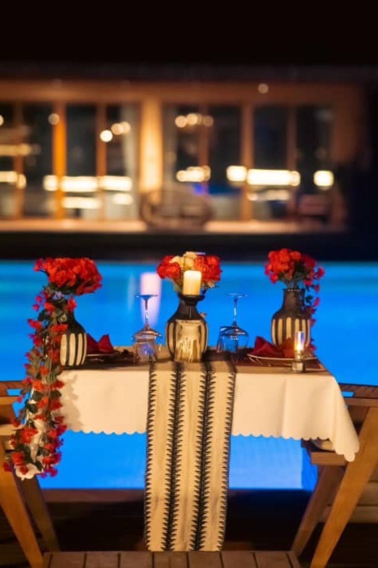 Romantic poolside dinner setup at night with glowing blue pool and candlelit table at Entikko Safari Lodge near Murchison Falls Uganda